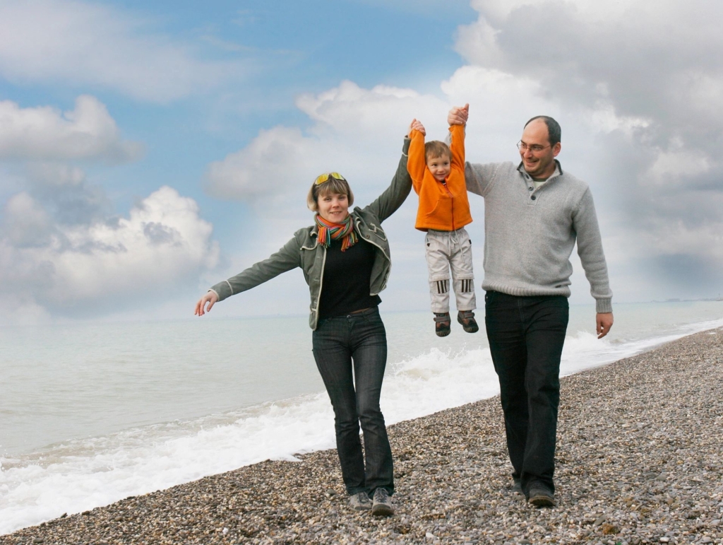 Happy family walking on a beach, representing adoption services at Vaughan Family Law, specializing in child, grandparent, and close-relative adoptions.